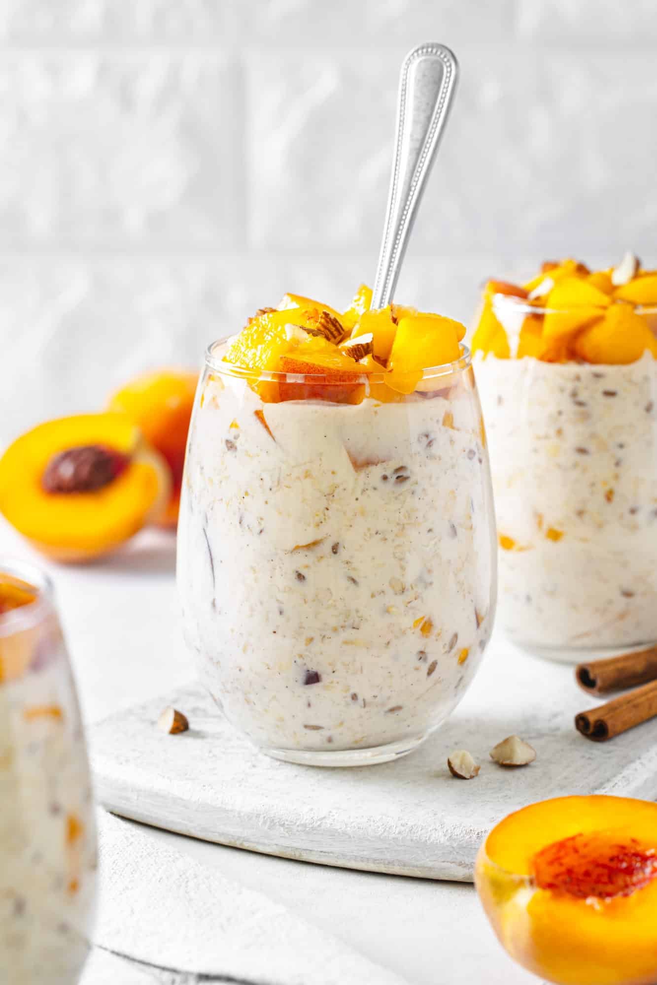 peach-overnight-oats-on-a-marble-board-with-a-spoon-and-with-cinnamon-and-peaches-in-the-background