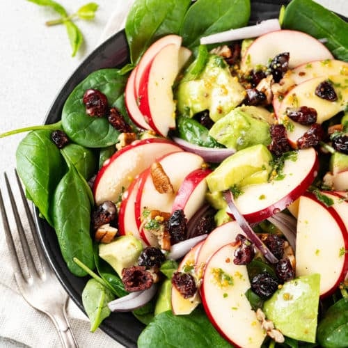 A bowl of apple, spinach, avocado salad.