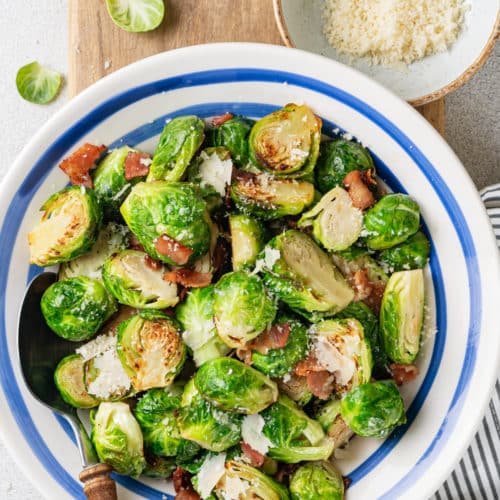 a blue and white bowl with brussels sprouts and bacon in it.