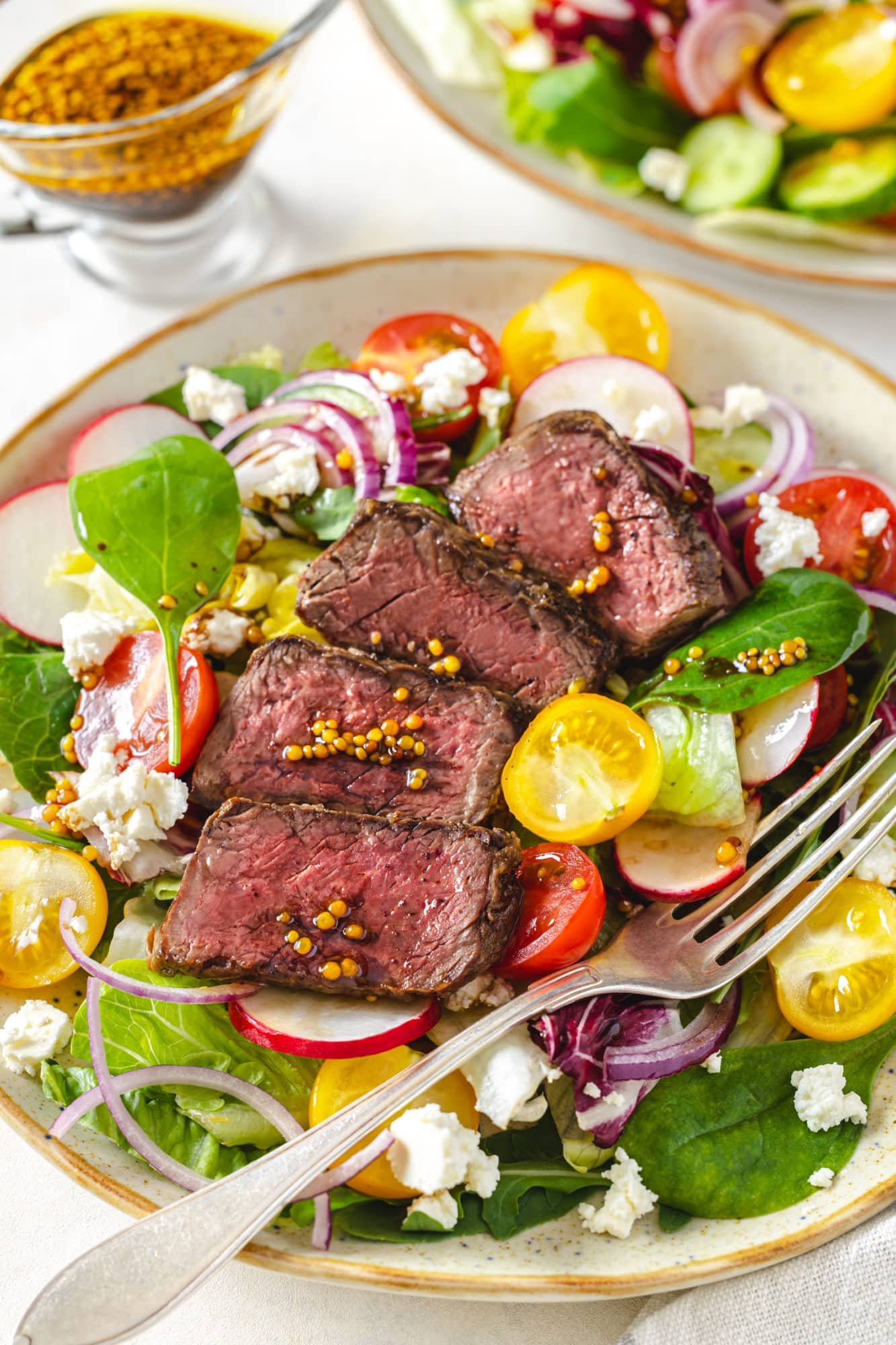 filet-mignon-salad-on-a-white-plate-with-a-fork