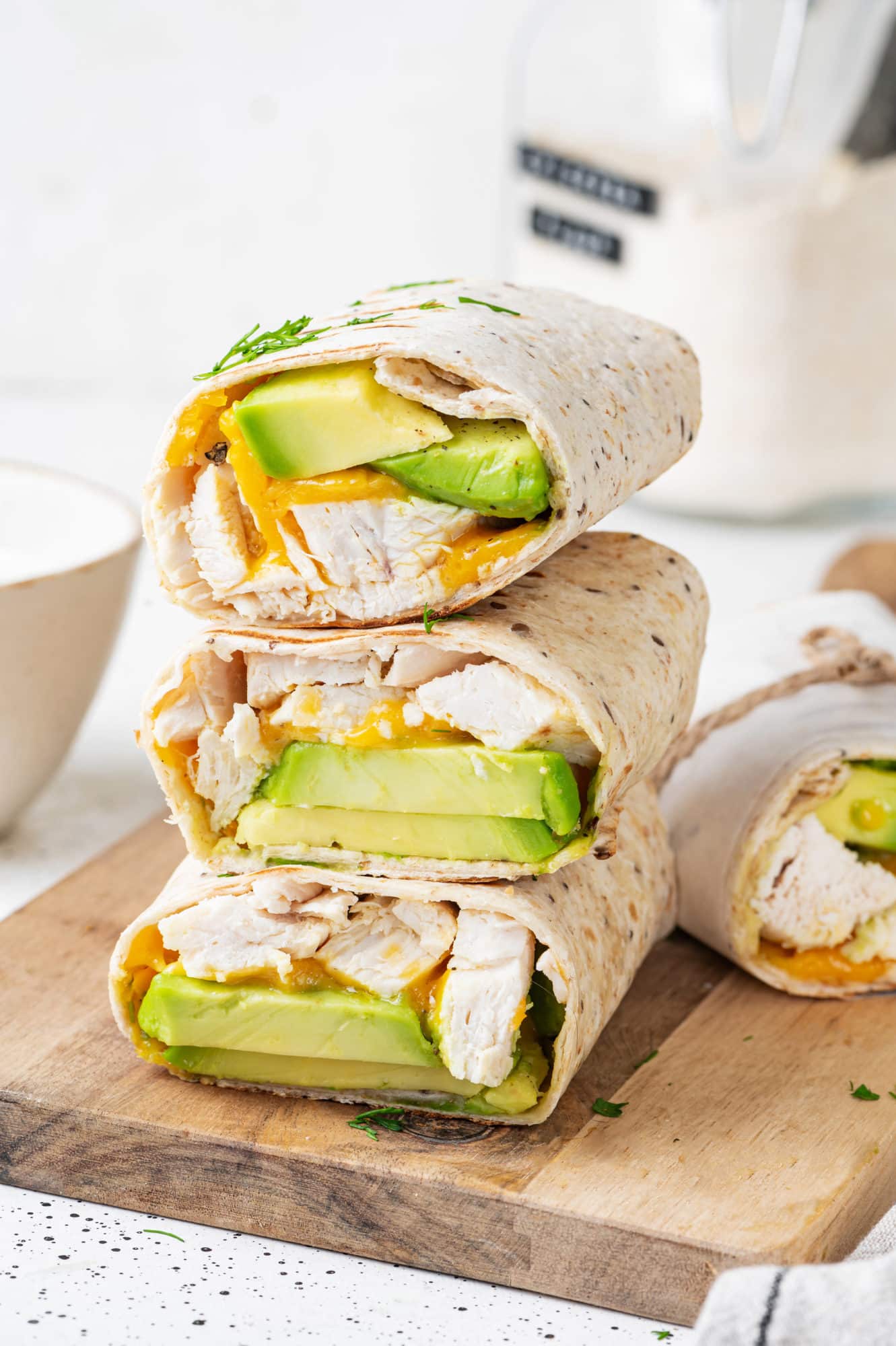 a stack of three chicken avocado tortilla wraps on a cutting board.