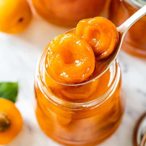 a jar with apricot jam with a spoon.