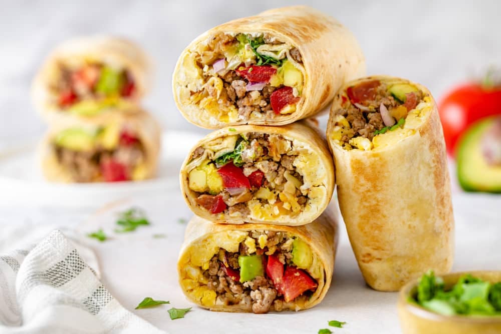 breakfast-burritos-halved-and-stacked-on-top-of-each-other-with-another-leaning-on-the-side