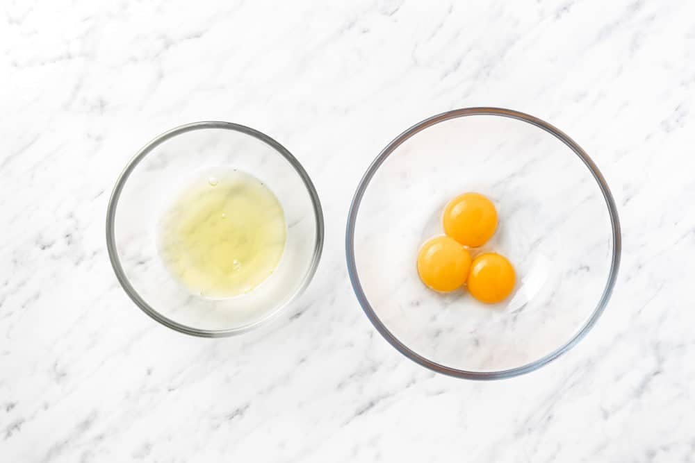 separated egg yolks in whites in glass bowls.