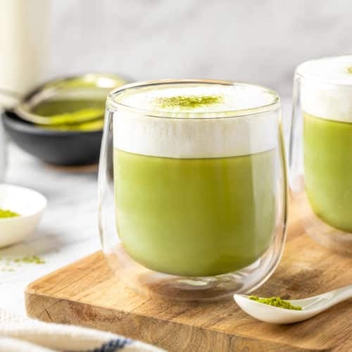 glasses filled with matcha latte with frothed milk on top.