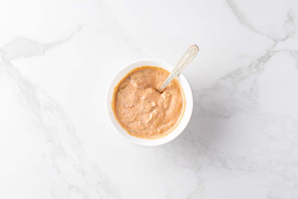 a white bowl with thousand island dressing and a spoon.