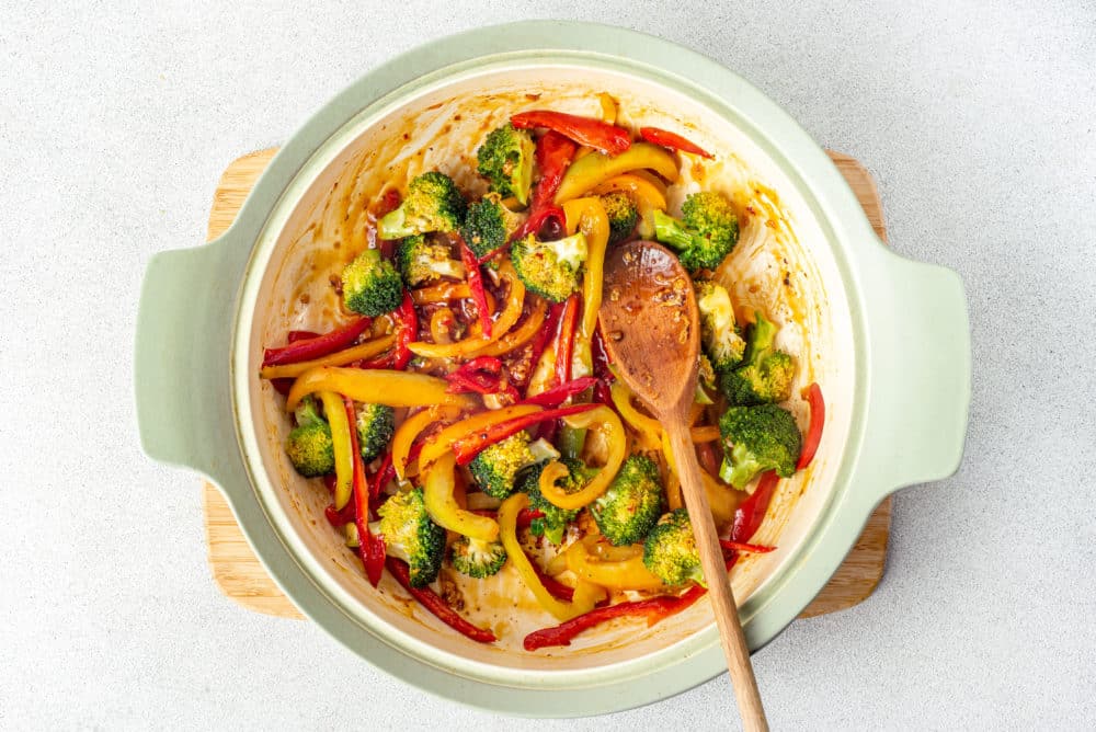 veggies-stir-frying-in-a-pot-with-a-wooden-spoon-on-a-wooden-board