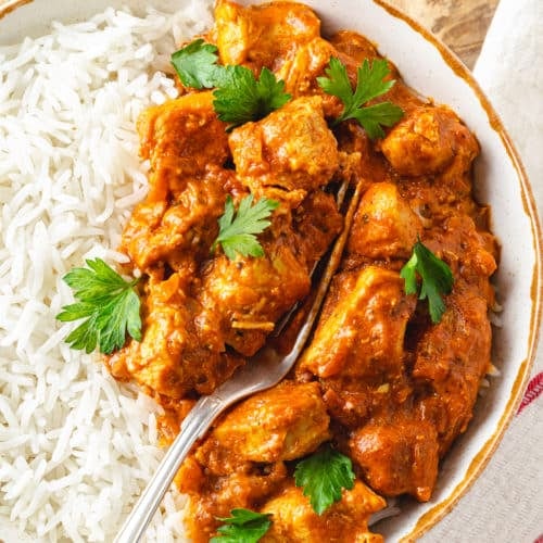 Indian butter chicken and rice in a bowl with a fork.