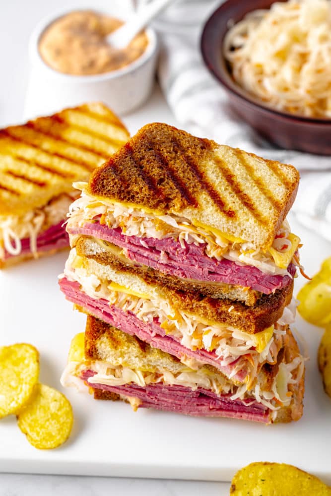 stacked reuben sandwiches on a white board.