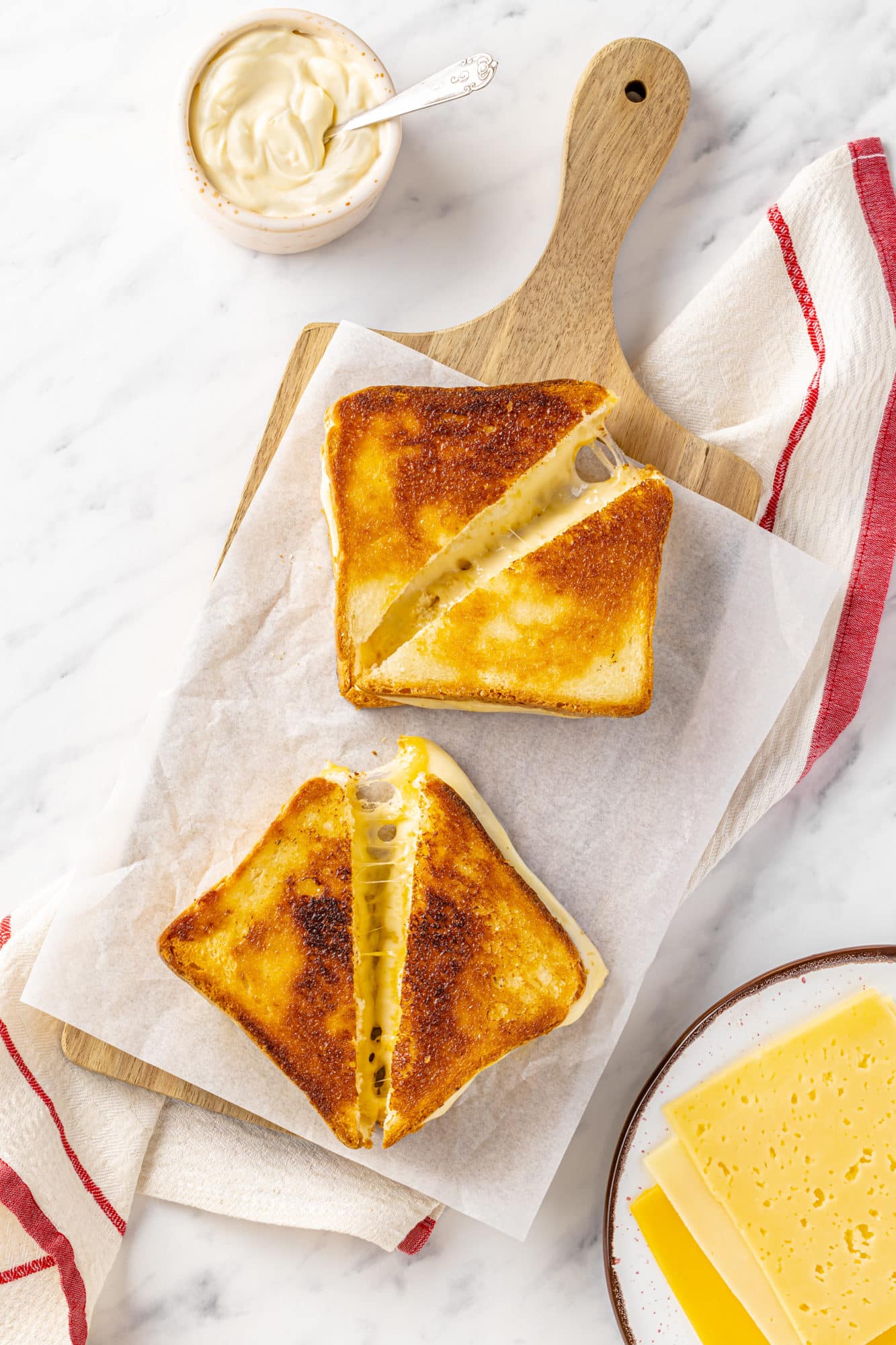 Sliced grilled cheese sandwiches on parchment paper.