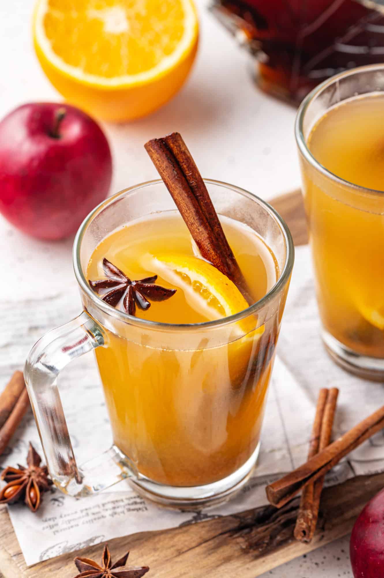 apple cider in a glass mug with orange cinnamon and star anise in the cider.