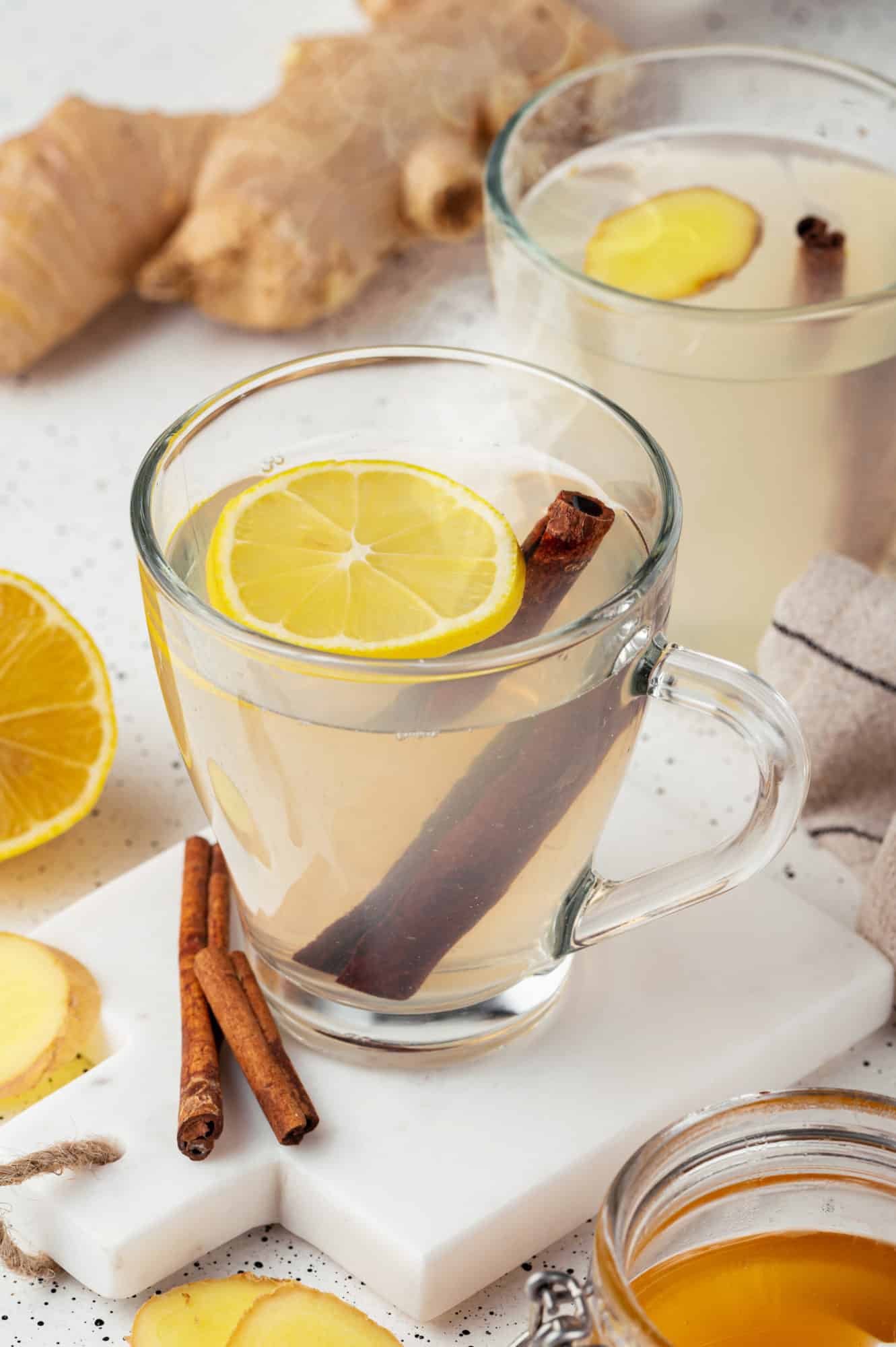 ginger-tea-in-glass-mugs-on-a-white-board-with-lemon-slices-and-cinnamon-sticks