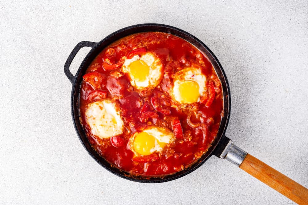 cooked eggs in a shakshuka base in a skillet.