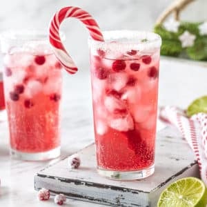 peppermint mocktail drink in a glass with a candy cane in the glass and sugar on the rim.