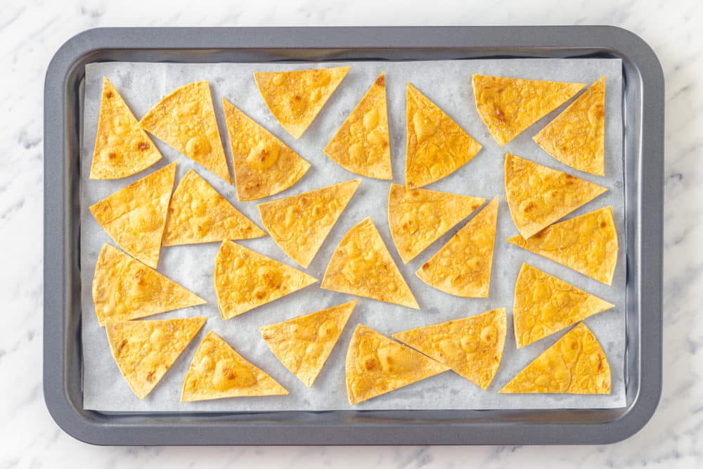 baked tortilla chips on a tray with parchment paper.