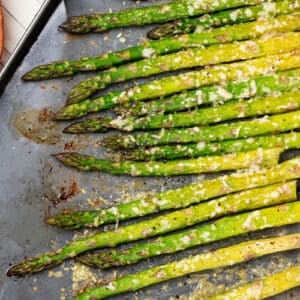 roasted asparagus with melted parmesan on a baking sheet