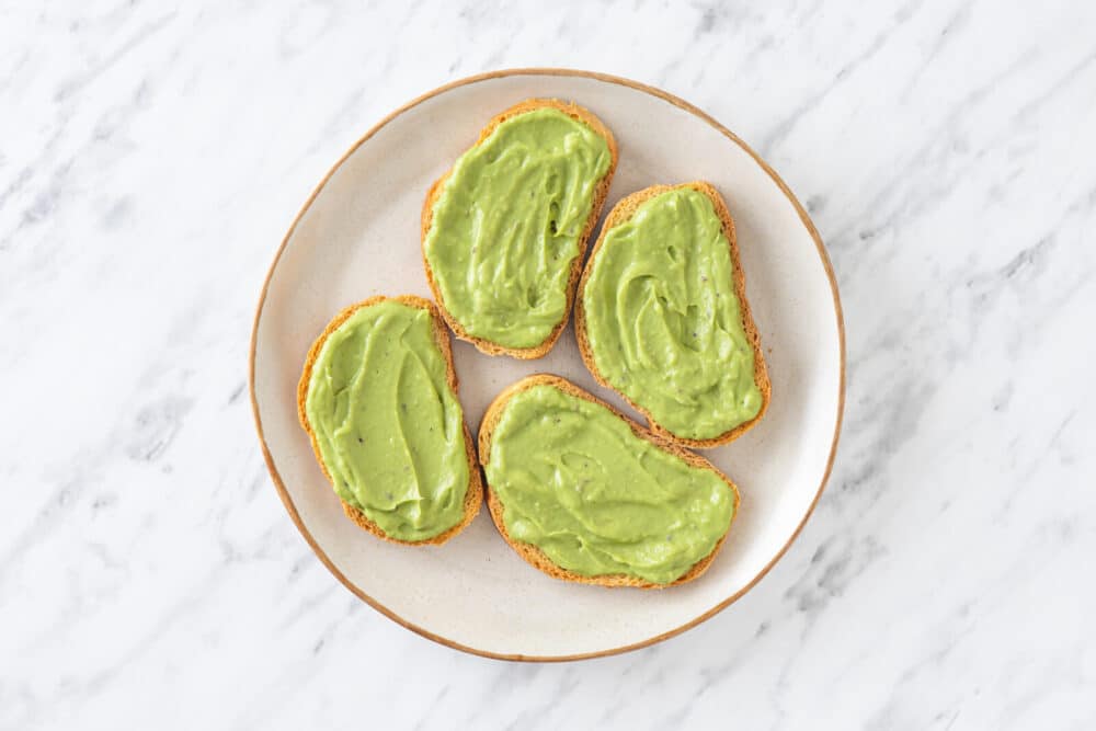 toast with avocado spread on each slice on a white plate.