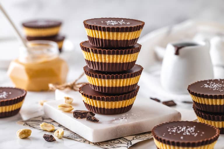 some stacked peanut butter cups with chocolate and peanuts on the side.