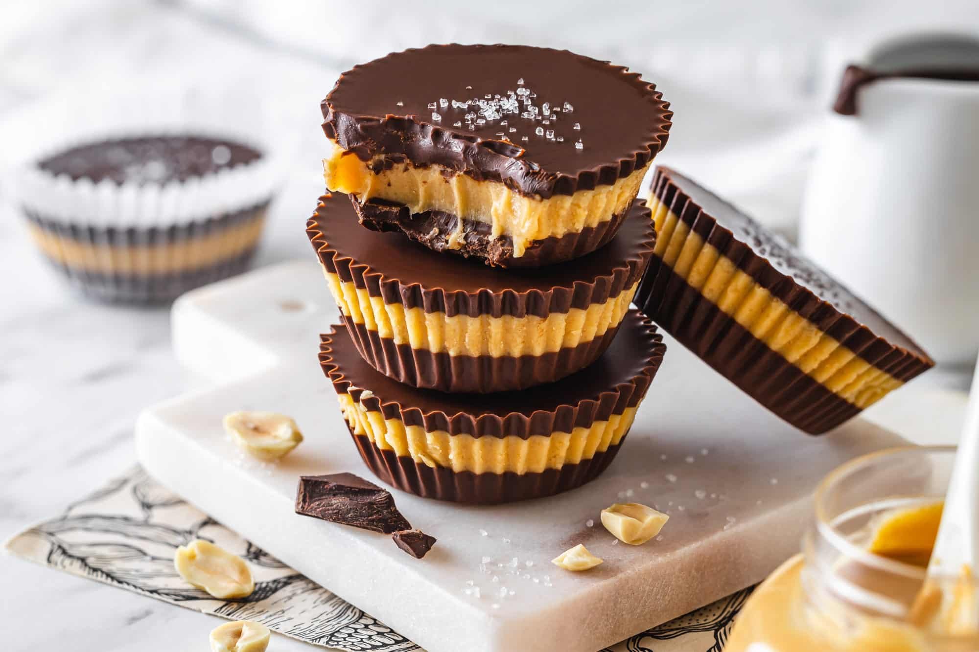 Dark chocolate cups stacked on a marble board with salt on the top cup.