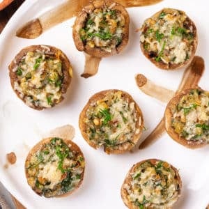 a decorated white plate with filled mushrooms on it and on a wooden board.