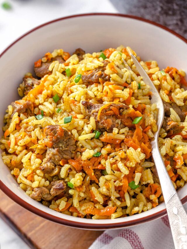 wooden board with a white plate with pilaf and beef with a fork.