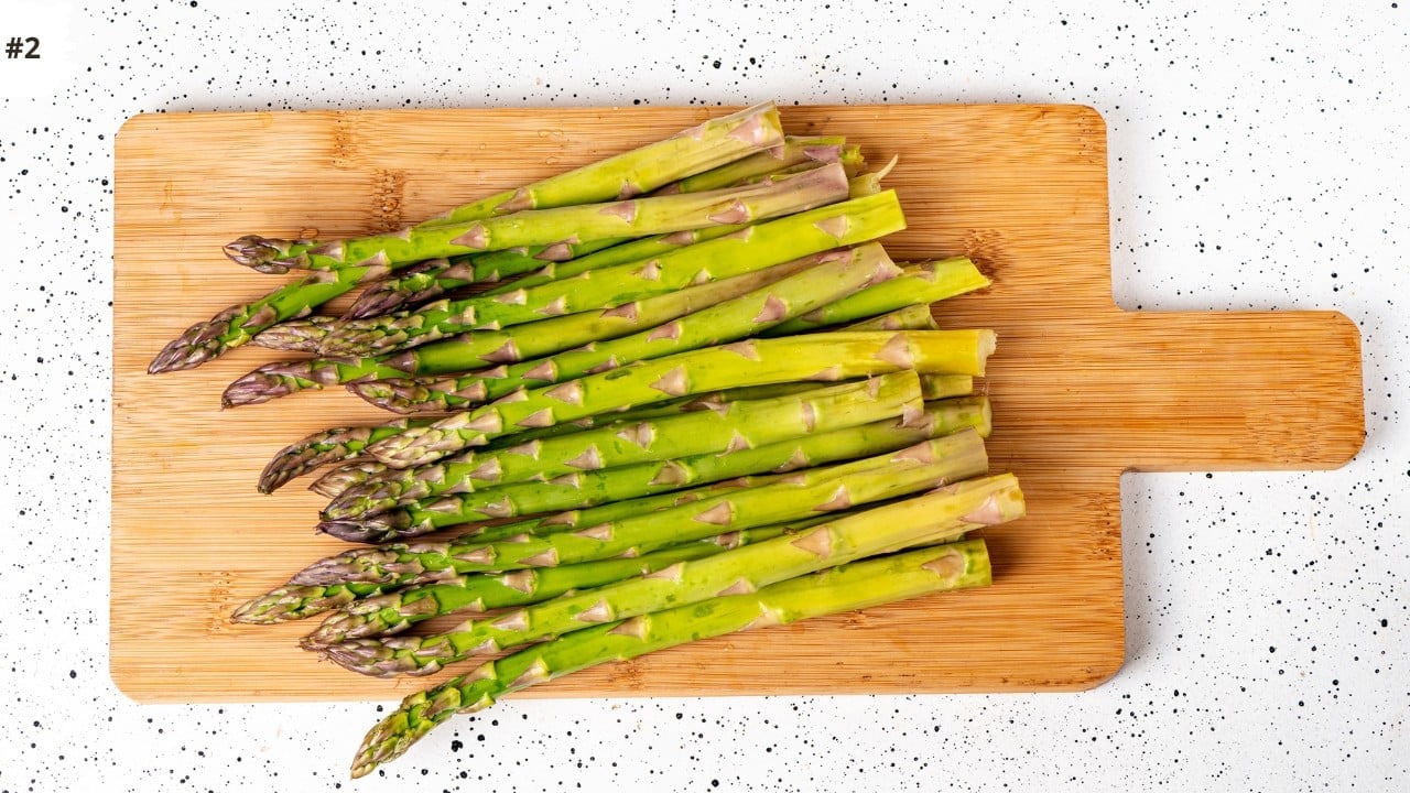 Asparagus with chopped ends on a wooden cutting board. 