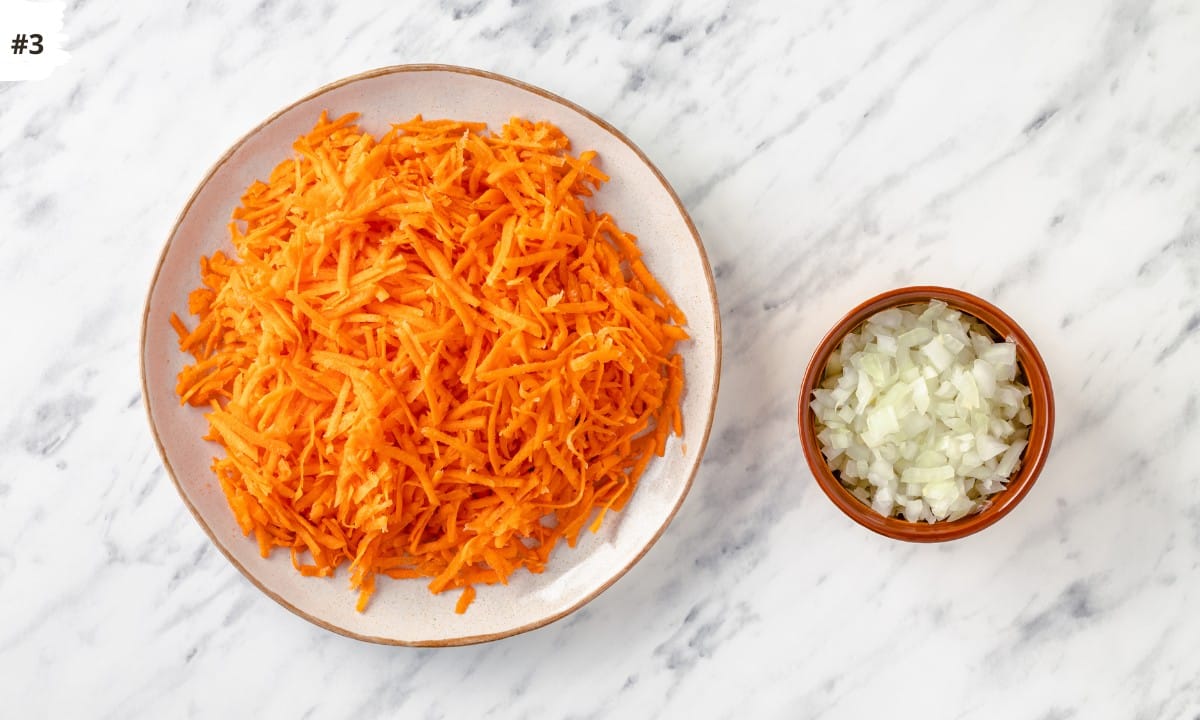 grated carrots on white plate with small brown bowl of chopped onion.