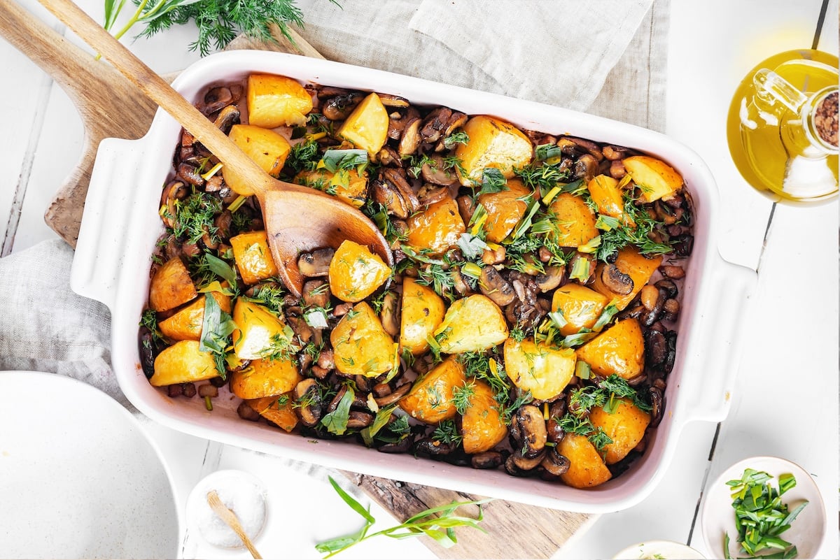 Fresh roasted potatoes and mushrooms side dish with dill in the dish and green onion in a small bowl on the side.