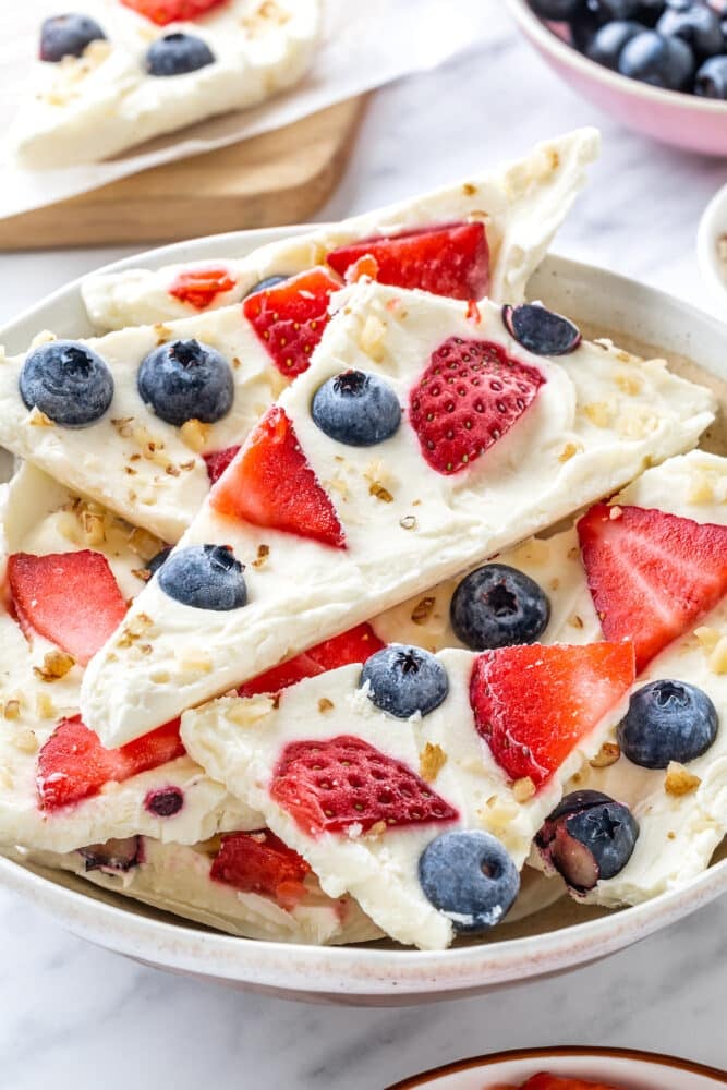 yogurt bark in chunks in a bowl with berries and nuts.