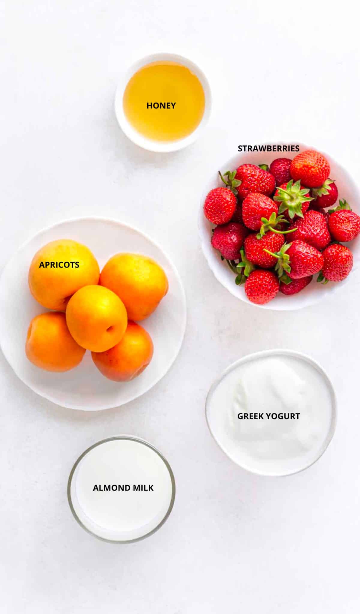 Ingredients for apricot smoothie with strawberries- honey, apricots, strawberries, almond milk, and greek yogurt. 