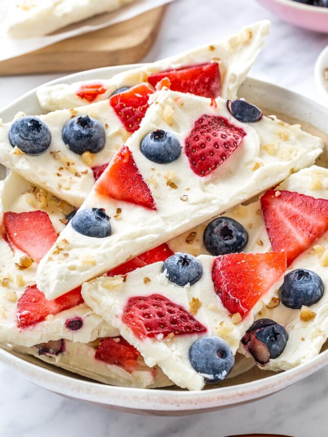 yogurt bark in chunks in a bowl with berries and nuts.