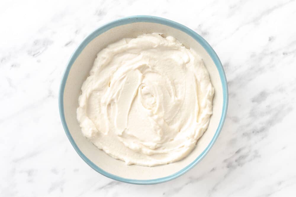 whipped softened cream cheese in white bowl.