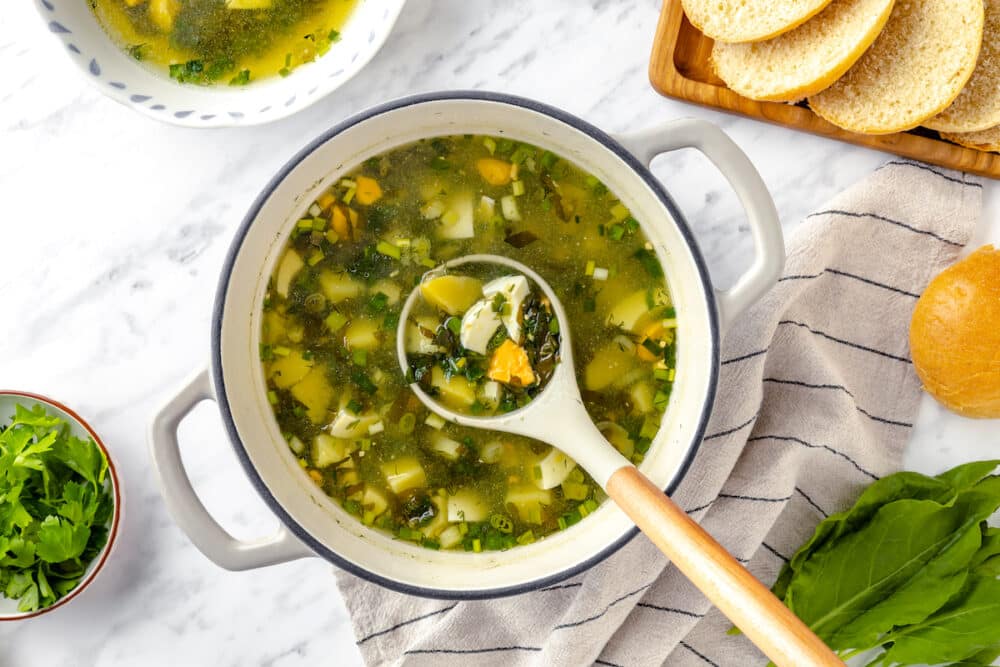 green sorrel soup in a pot with a ladle.