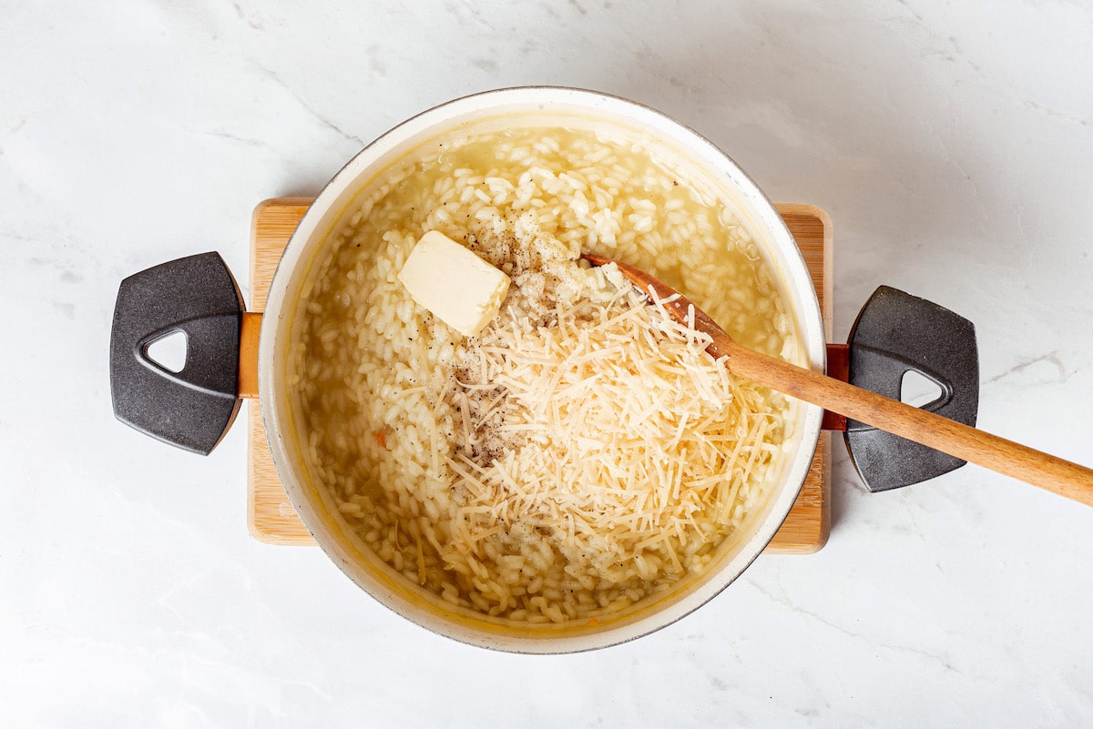 pot of risotto with parmesan and a pat of butter on top waiting to be stirred in