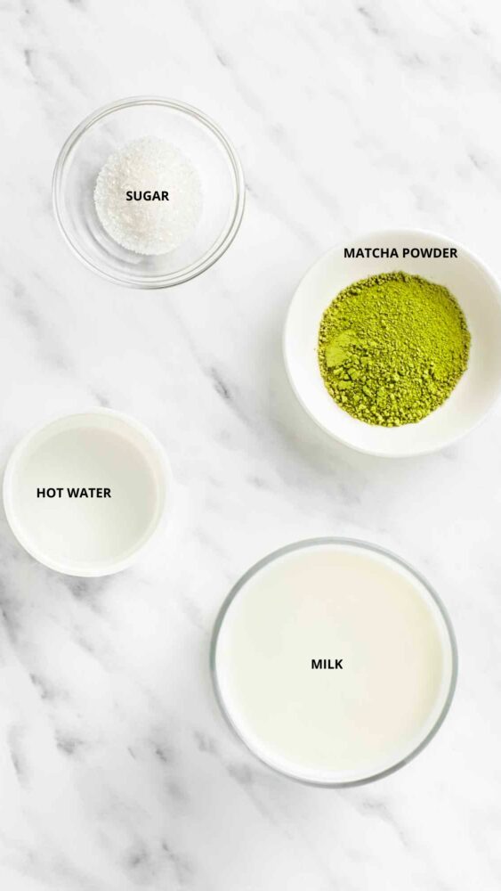 Homemade matcha latte recipe ingredients in bowls- sugar, matcha powder, hot water, and milk.
