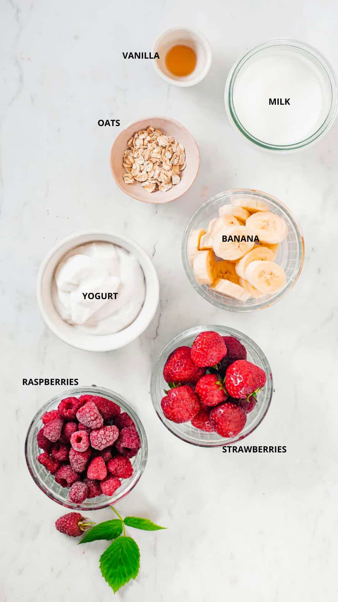 Berry banana oat smoothie ingredients- milk, vanilla, oats, yogurt, banana, strawberries, and raspberries.