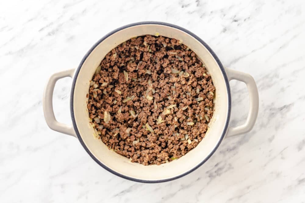 in a soup pot ground cooked beef with chopped onion.