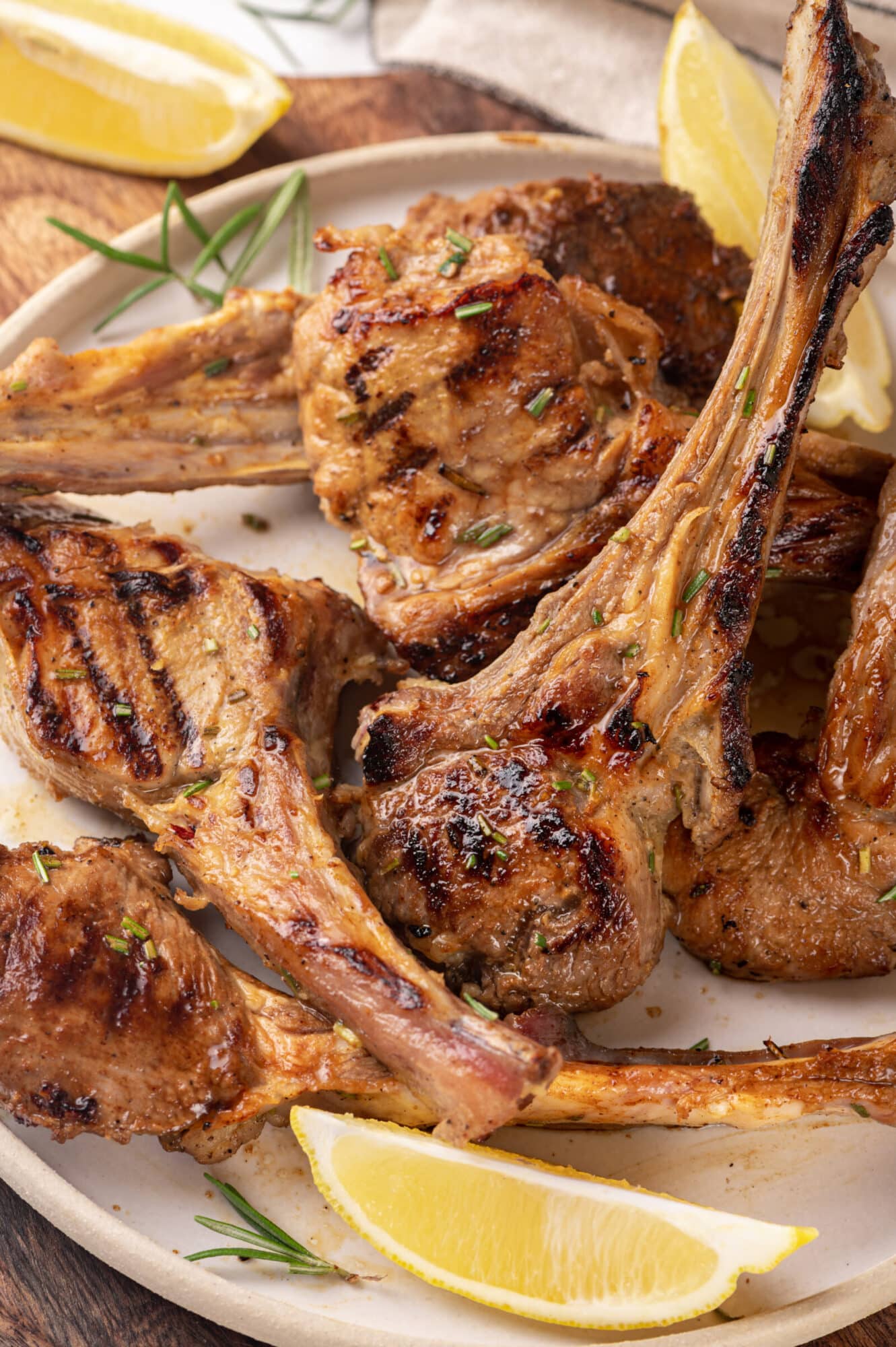 grilled lamb chops with lemon wedges on a white plate.