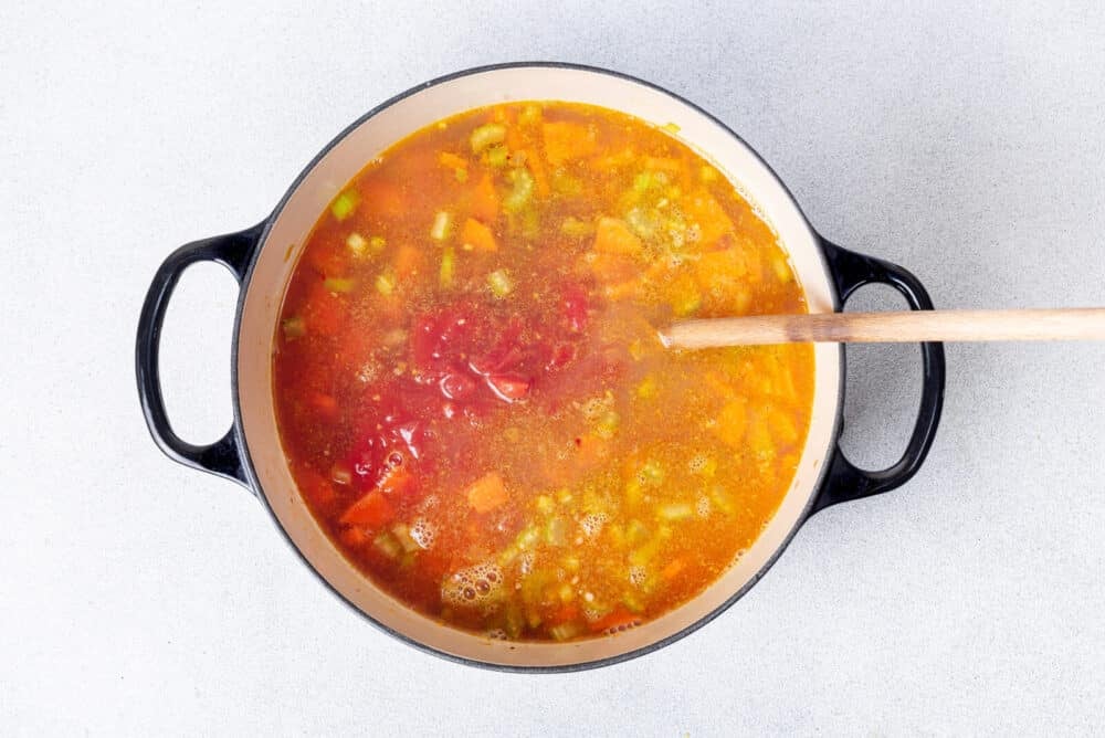 Canned tomatoes, spices and broth are added to the vegetables.