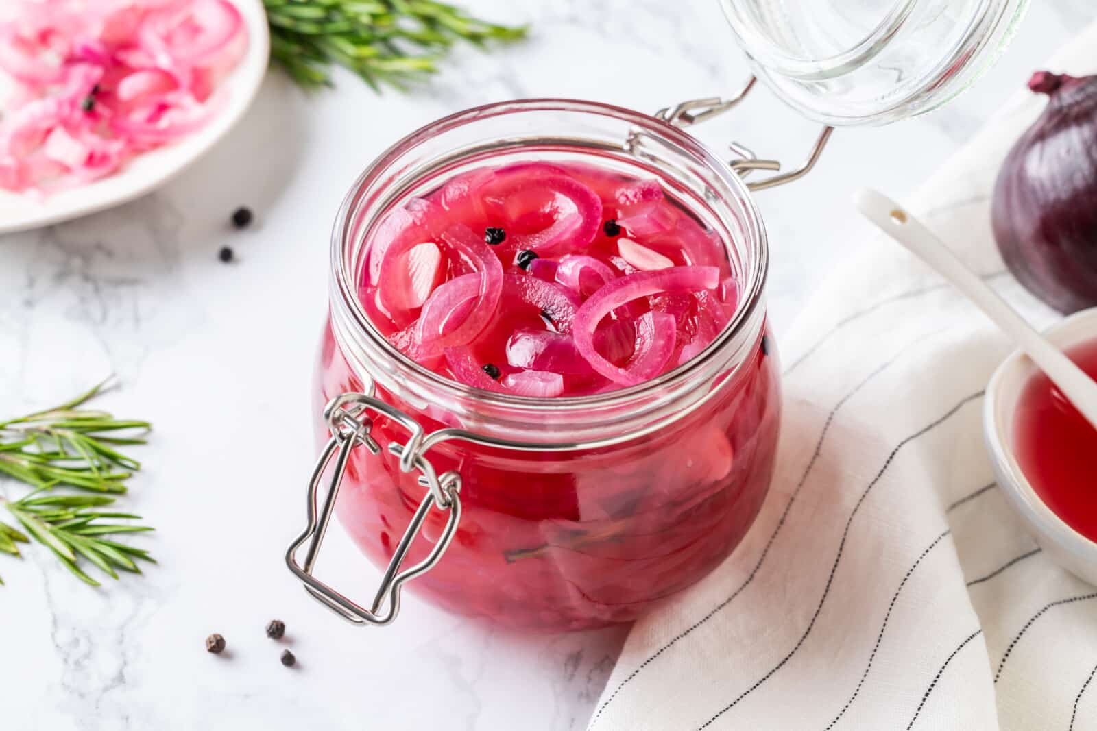 Pickled onions in a jar with peppercorns.