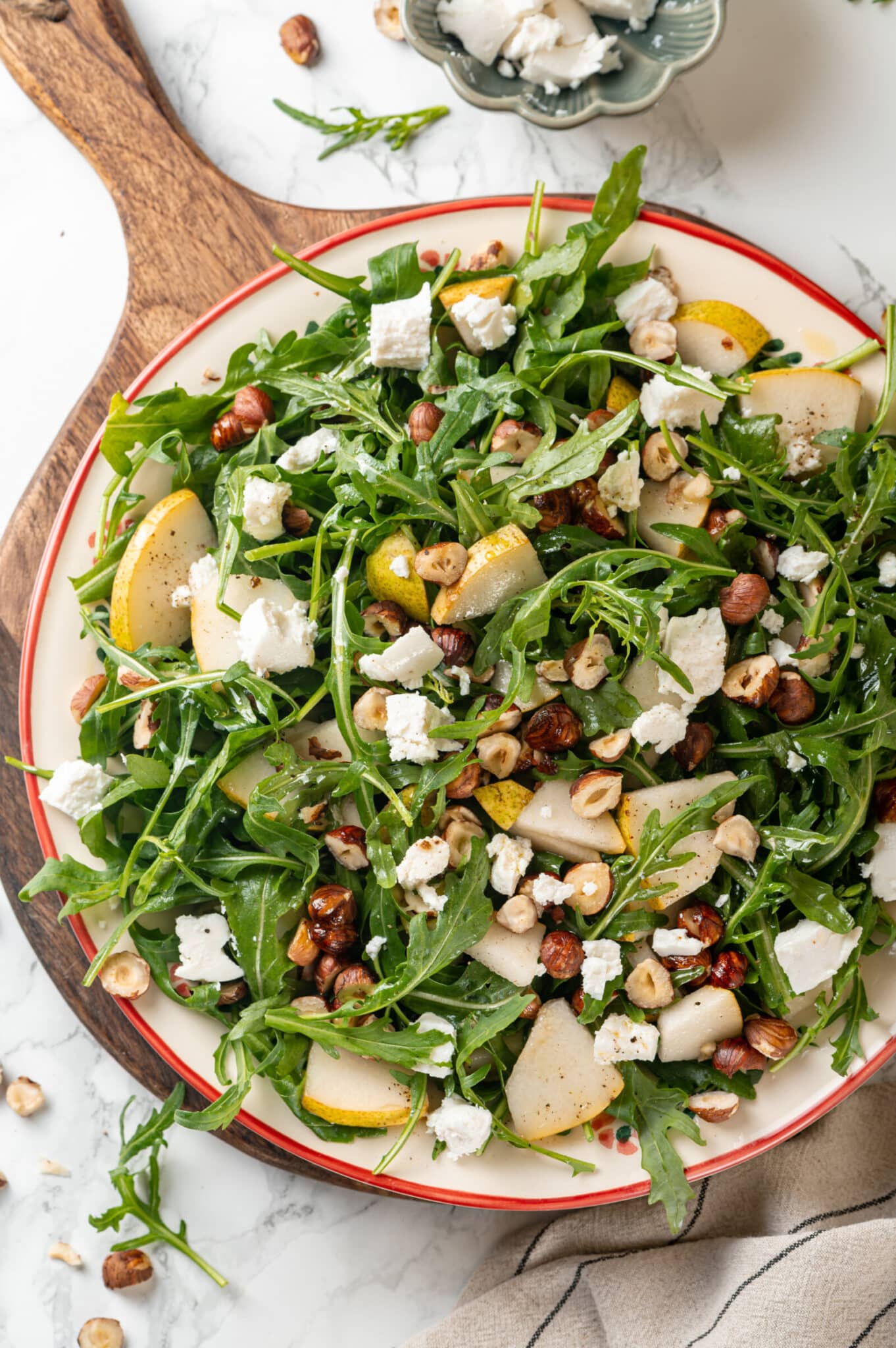 Leafy arugula salad with pears, goat cheese, and hazelnuts as a topping.