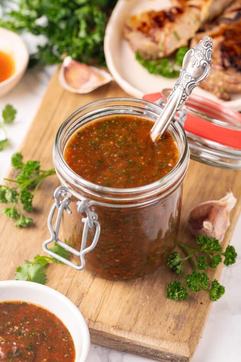 Red meat sauce in a glass jar with a spoon.