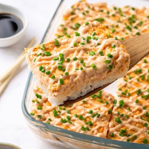 A piece of salmon sushi bake atop a wooden spoon.