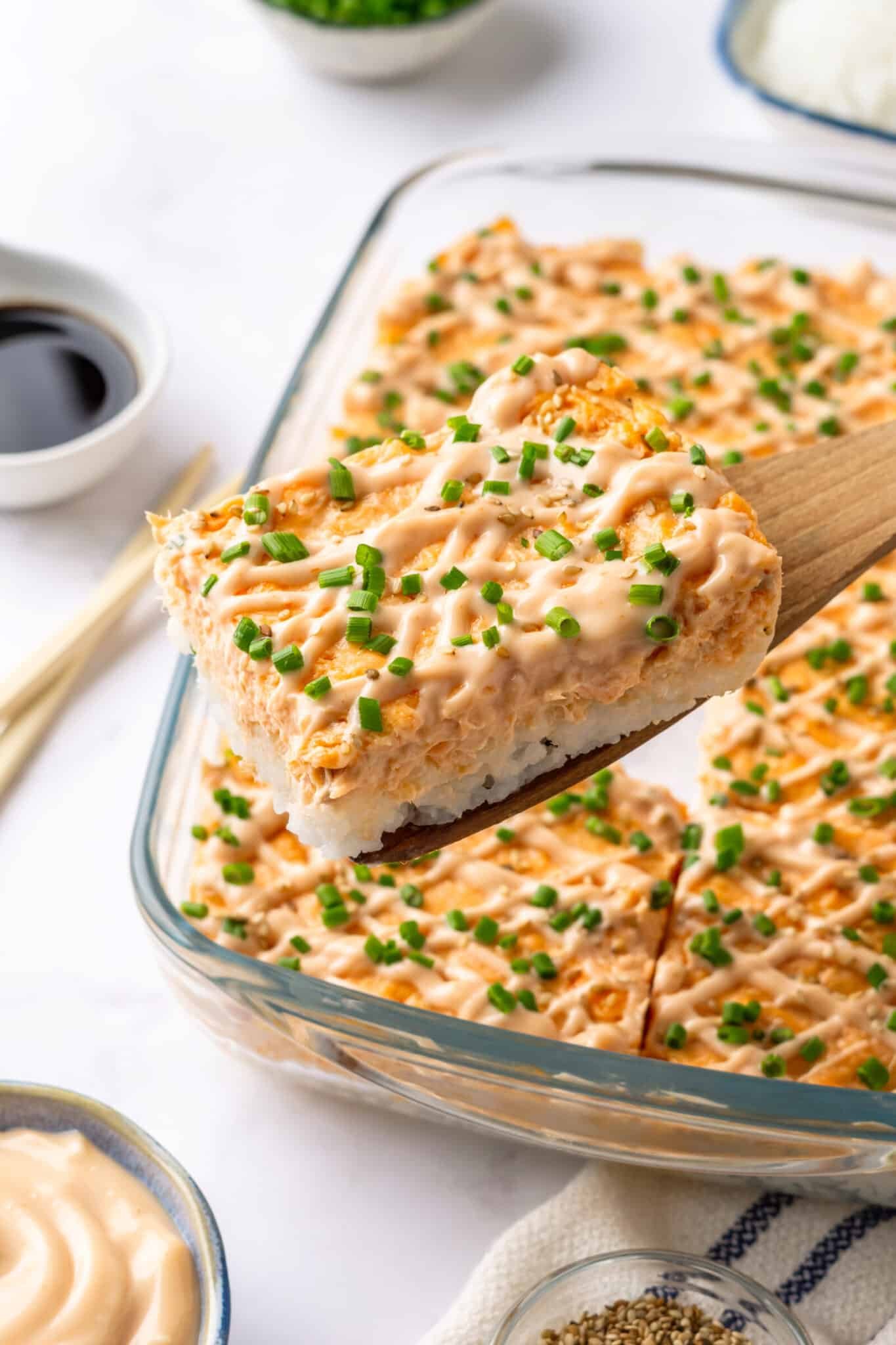 A piece of salmon sushi bake atop a wooden spoon.