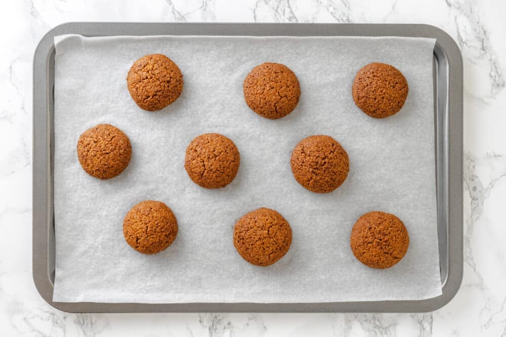 Almond cookies freshly baked atop a baking sheet.