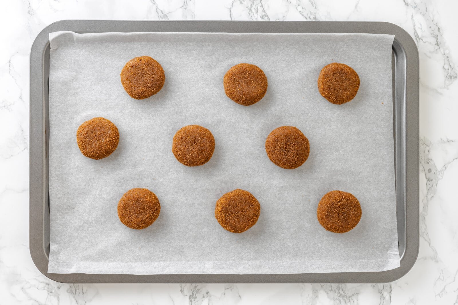 Almond snickerdoodle cookies ready to bake on parchment paper and a cookie sheet.