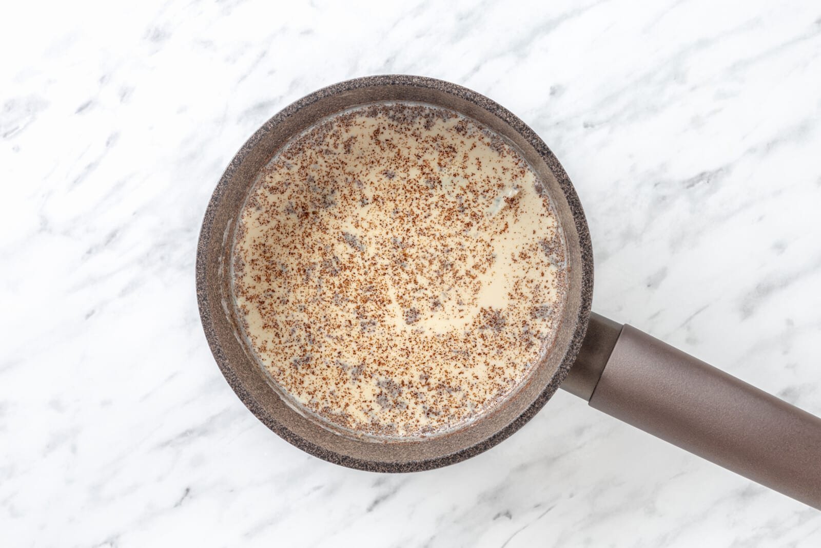 Chai Tea Latte with Warm Spices Chai spices in milk in a saucepan.