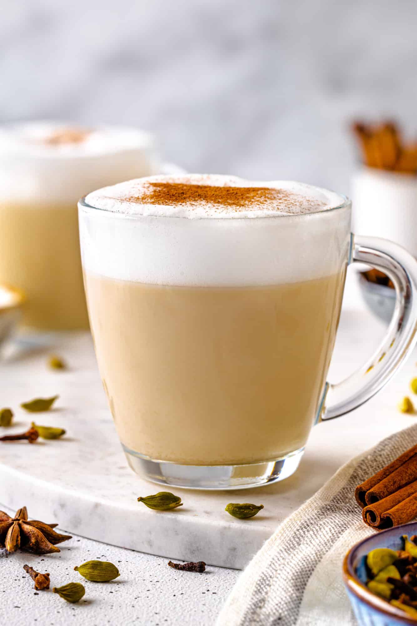 Chai Tea Latte with Warm Spices Chai tea latte in a glass with frothy milk on top and cinnamon sprinkle.