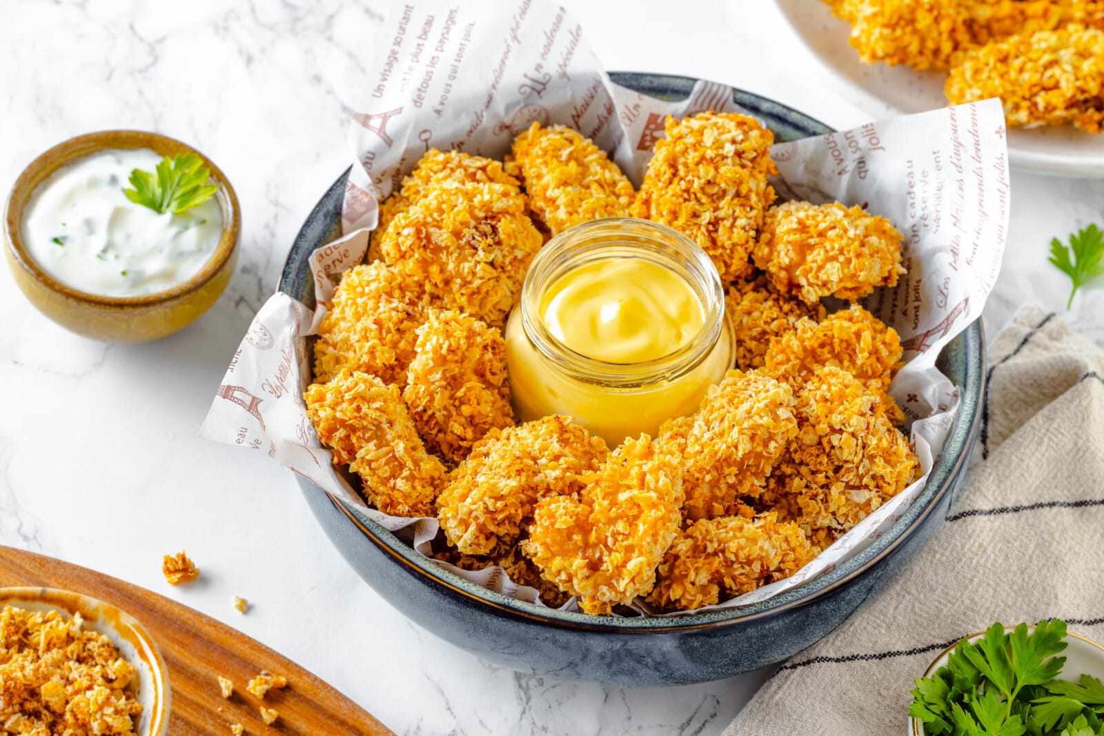 Chicken nuggets in a bowl with dip, ready to eat with more ranch dip on the side.