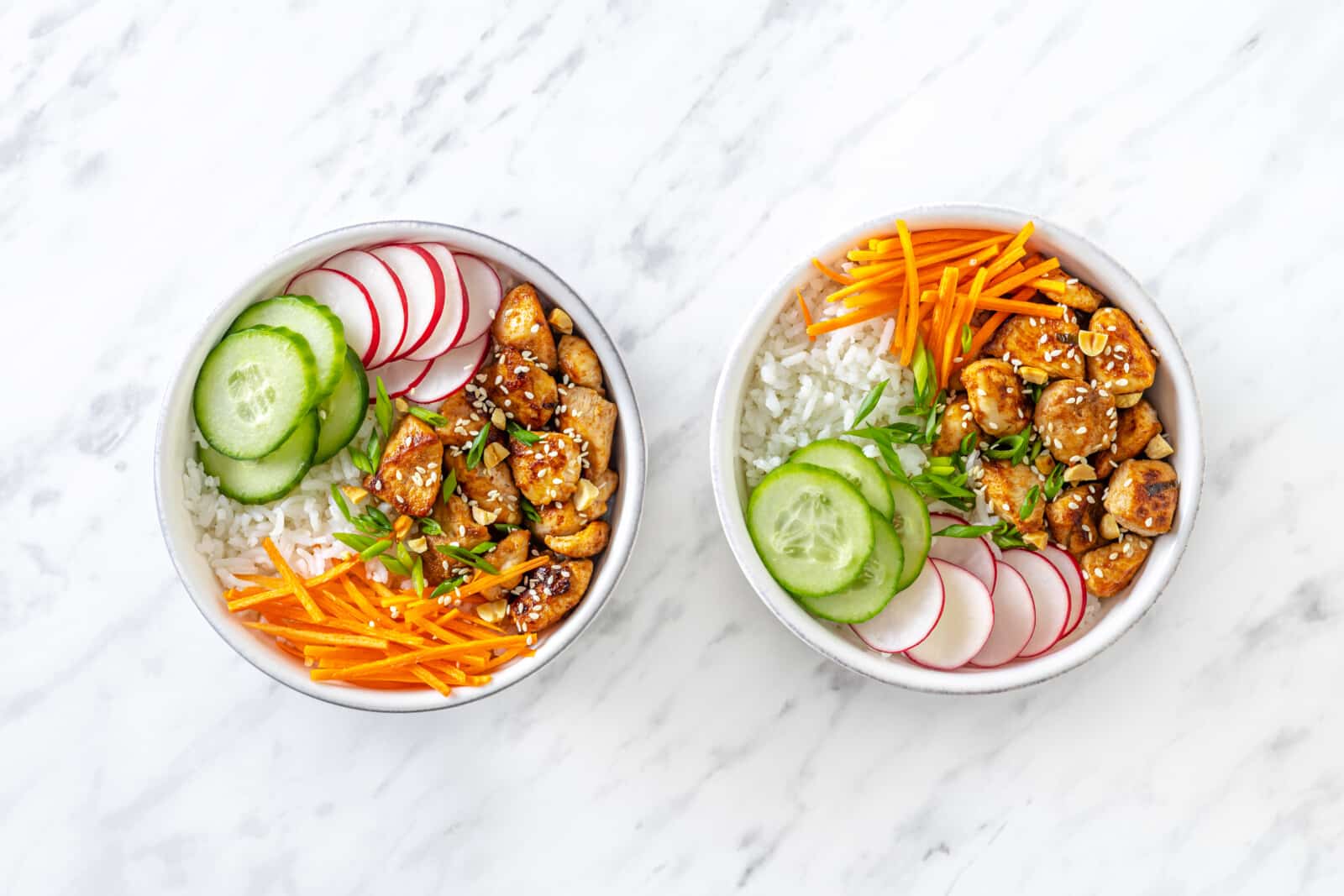 Easy Chicken Rice Bowls with Fresh Veggies Chicken rice bowl assembled with rice on the bottom, laid out veggies, and chicken on top.